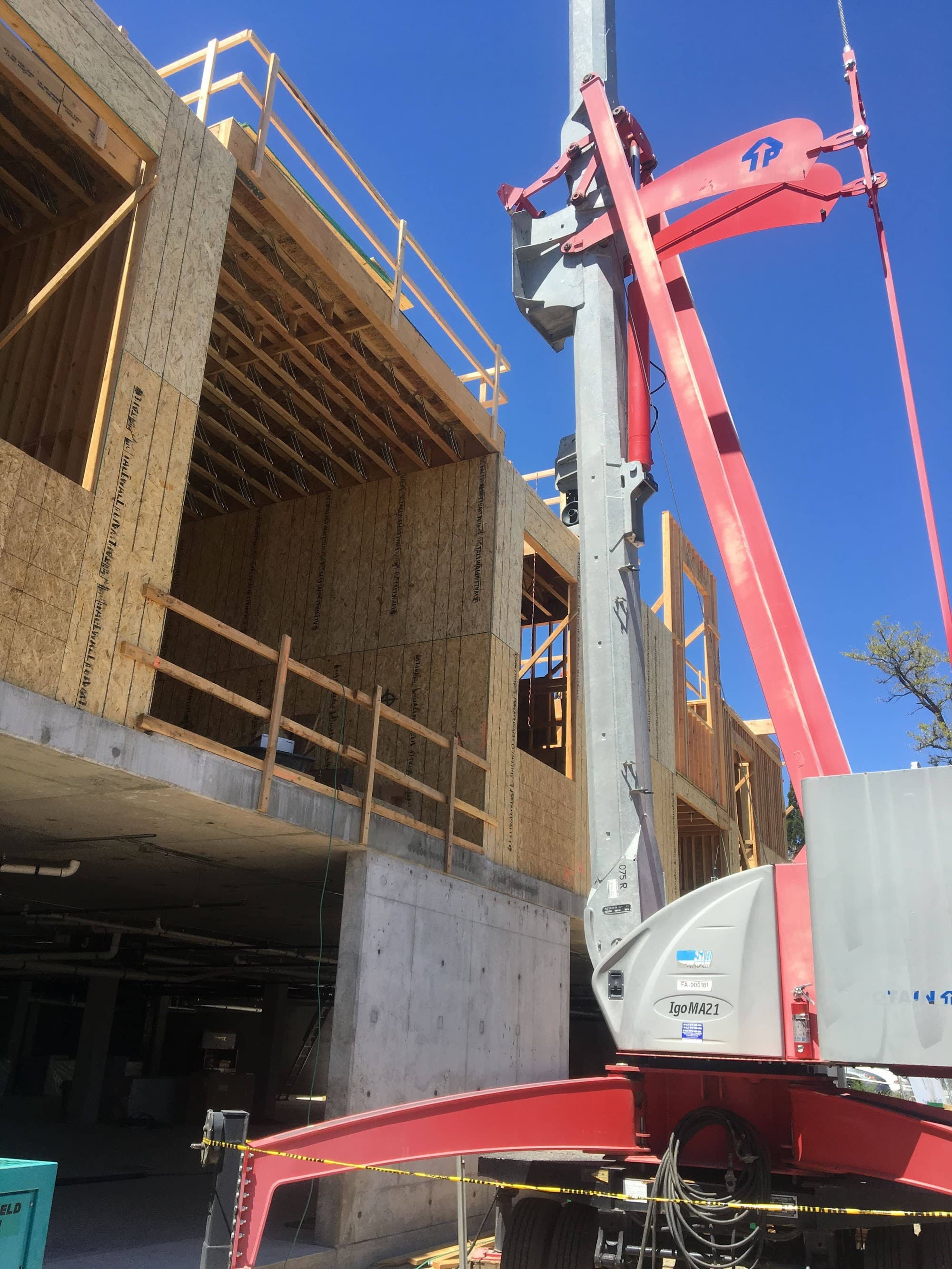 Multi-story wood-frame apartment over concrete podium with crane — multi-family structural engineering by Palisade Engineering