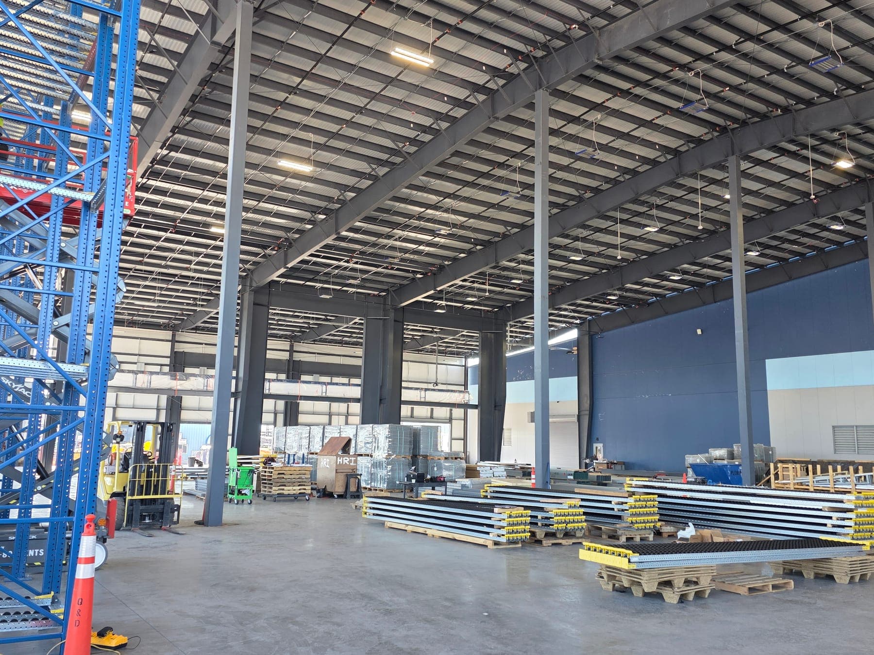 Interior of a finished metal building with tapered steel frames, pallet racking, and a forklift